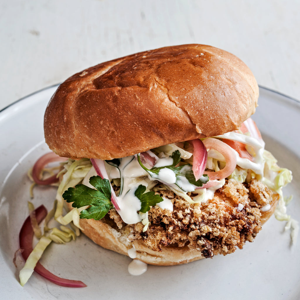 Fried chicken sandwich on a bun with coleslaw and white sauce